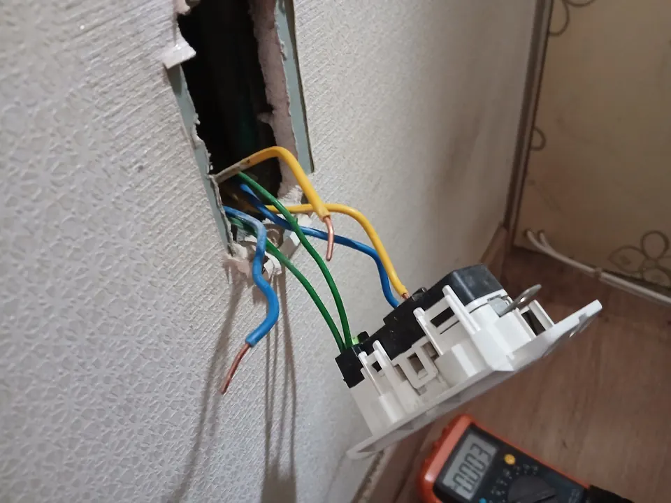 테스터기로 점검하며 벽 콘센트 배선을 연결하는 모습