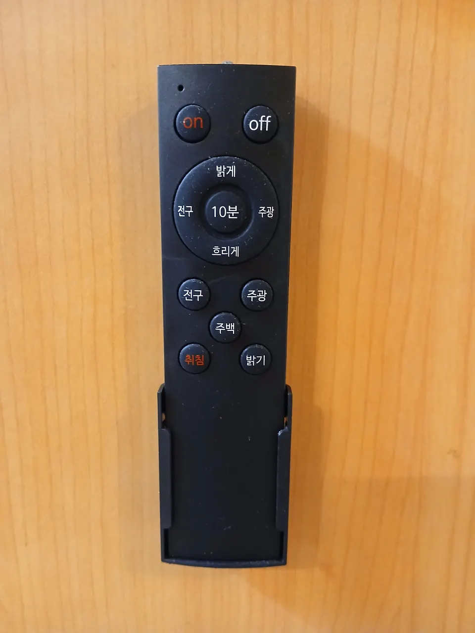 원목 벽면 거치대에 꽂아 둔 LED 방등용 무선 리모컨