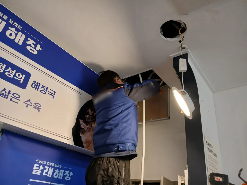 천장 점검구를 열고 매립등 배선을 연결하는 작업 모습