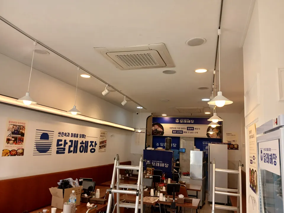사다리를 세우고 레일 조명을 설치 중인 식당 내부