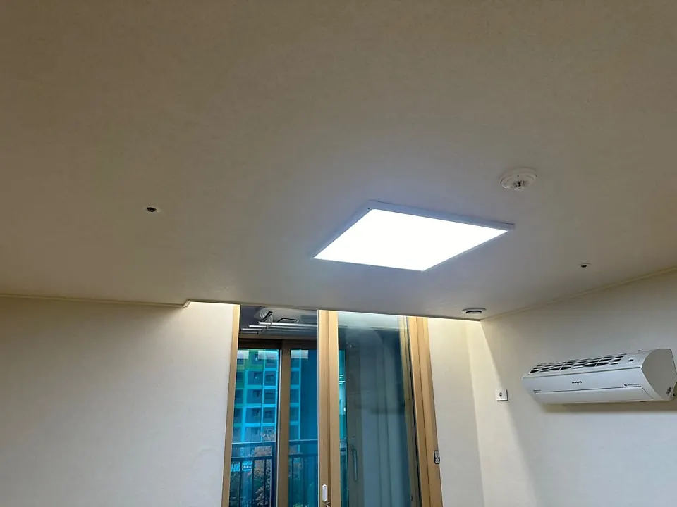 벽걸이 에어컨이 있는 방 천장의 사각 평판등과 간접조명
