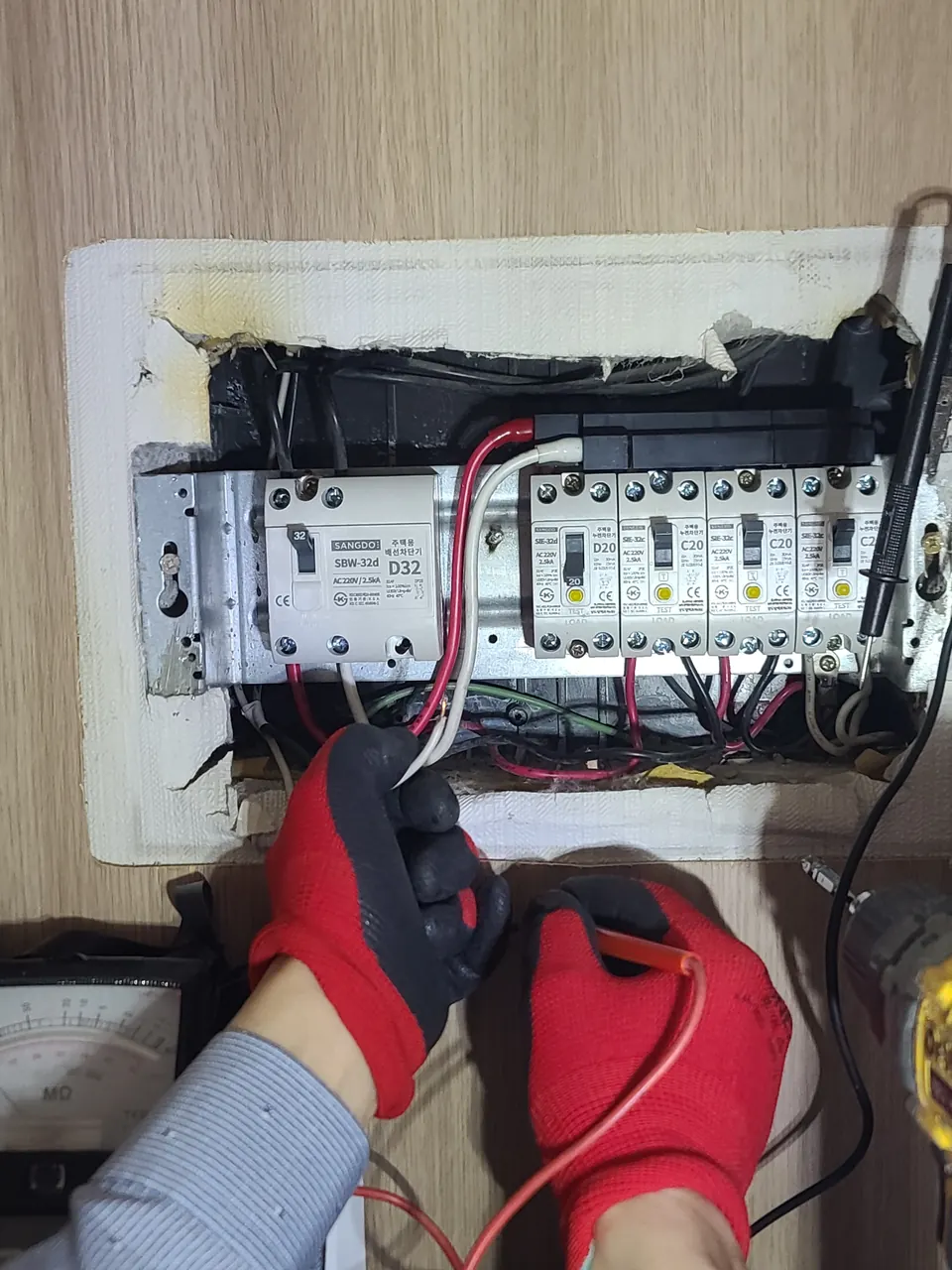 장갑을 끼고 분전함 회로를 메가테스터기로 측정하는 모습